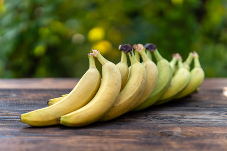 green bananas are still easy to fresh on a brown wooden table, green backgroundの写真素材