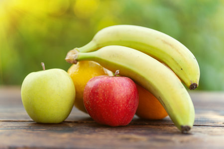 Still Life Fruits - Bananas and Apples on a wooden table against a blurred background of nature.の写真素材