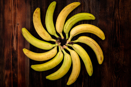 Bananas on brown wooden table top view. Figured position of bananas in geometric shape. bananas are laid out in the shape of the sun.の写真素材