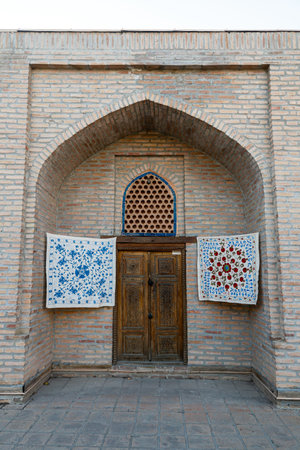 small carpets hang on the wall in front of the entrance to the souvenir shop in Samarkand, Uzbekistan.の写真素材