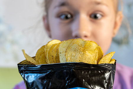orange chips. Appealing young girl with open mouth and putting chip inside. A teenage girl looks...