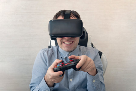 Young man trying virtual reality at home, using headset VR glasses and holding joystick, playing...