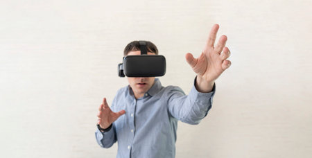 Businessman using virtual reality glasses in office. Man in VR headset standing touching objects in...