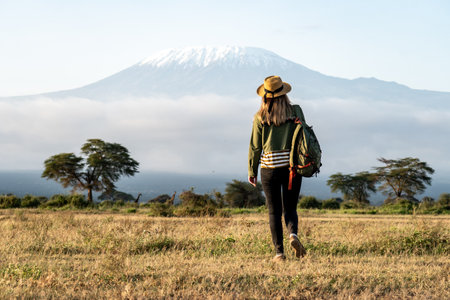 A young beautiful girl walks through the savannah against the backdrop of Mount Kilimanjaro during a...