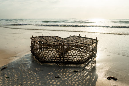 Old fishing cage in water of the Caribbean sea under blue tropical sky. Cage fishing and low tide in the French Antilles. African fishing trap for catching fish.の写真素材