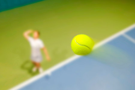 blurred background, focus on the ball. effect of movement. Top view of female tennis player with raised racket on tennis court. hitting with a racket in tennisの写真素材