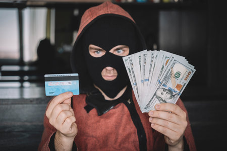 a thief with a credit card and cash dollars. The concept of stealing money from a bank account.