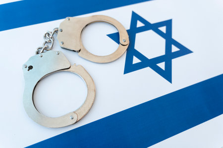 Crime and justice concept in the country of Israel. Handcuffs and an Israeli flag on the backgroundの写真素材