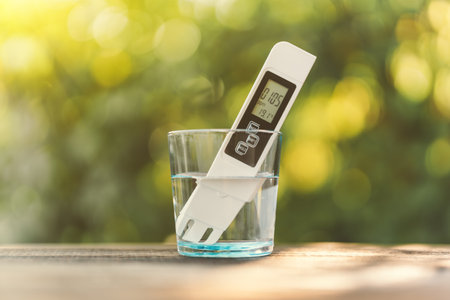 Electronic pH meter in a glass of water. TDS measurement of water. Blurred background of natureの写真素材