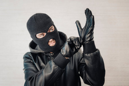 A thief in a black jacket. A man in a black balaclava with an evil expression on his face. An...