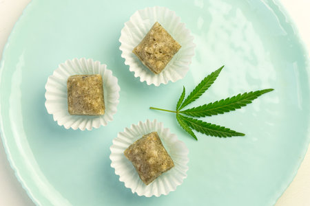 Sweets with CBD oil. Colorful candy with cannabis leaves. Marijuana leaf on blue background. ingredient in food for relaxation. Top view, flat lay.の写真素材