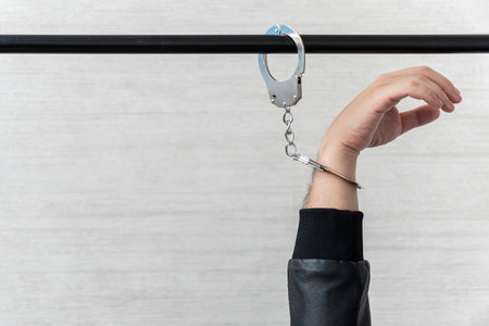 handcuffed hand is strapped to pipe. concept of arrest and incarceration. A prisoner in prison.の写真素材