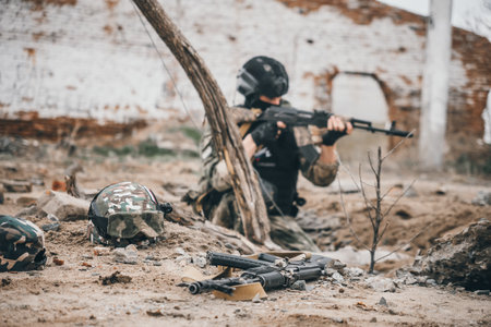 The submachine gunner is sitting in the trench. The focus is on guns and helmets.. A special forces soldier storms a destroyed building. The concept of war and military exercises.の写真素材