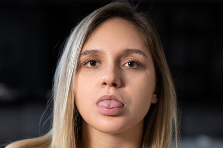 attractive positive woman, blonde, grimaces, smiles, attracts attention, looks in mirror shows tongue playfullyの写真素材