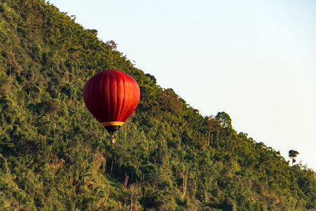 Red hot-air balloons flying over the mountain and green rice field in Vang Vieng, Laosの写真素材