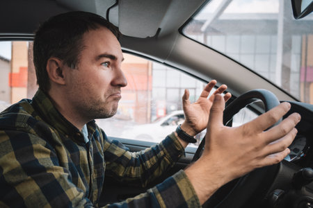 Emotional man in car. Aggressive driving behavior. An angry man gestures, swearing at traffic jams...