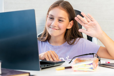 Joyful curly girl holding and using laptop greeting wave hand, browsing social network apps, surfing...