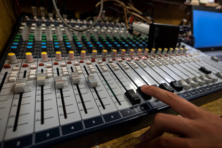 The hand adjusts the scale to the sound workstation next to the desktop. A mixing console for setting up and recording close-up sound. Recording studioの写真素材