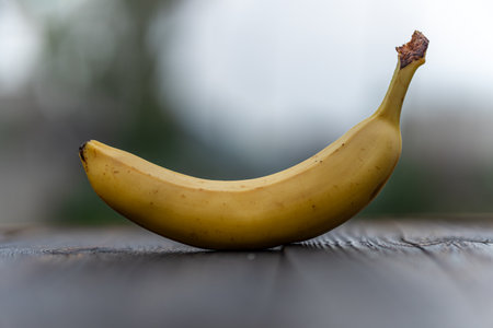 one banana on a wooden board with blurred backgroundの写真素材