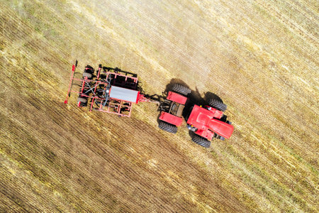 tractor working in a field on bright sunny day. concept of work in a fields and agriculture industry. Plowing the land with flow using a tractor. harvesting, tillage of soil and plants. aerial view,の写真素材