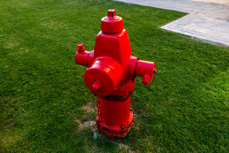 A bright red fire hydrant standing on a sidewalk, symbolizing safety and emergency response. A common urban element with bold color and industrial design.の写真素材