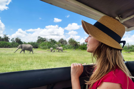 Young woman discover african nature by car Tanzania safari. A Caucasian girl in a hat looks at animals in the savannah. The concept of travel and adventure in the wild.の写真素材