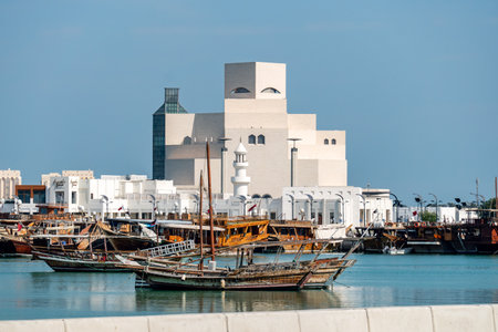 Traditional Qatari dhow boat docked with the Museum of Islamic Art in Doha in the background. A...