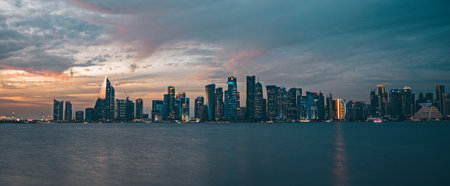 Panorama of Doha, the capital of Qatar. View of Doha from the sea. Skyscrapers on a rose and blue background. Modern architecture of Doha glowing houses in the dark in the evening, view from the sea.の写真素材