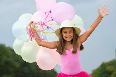 little girl running with balloons in her handの写真素材