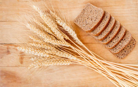 Rustic bread and wheat on an old vintage planked wood table. Old wood background with free text space.の写真素材