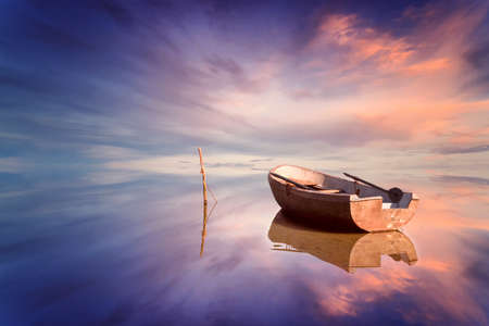 Lonely boat and amazing sunset at the seaの写真素材