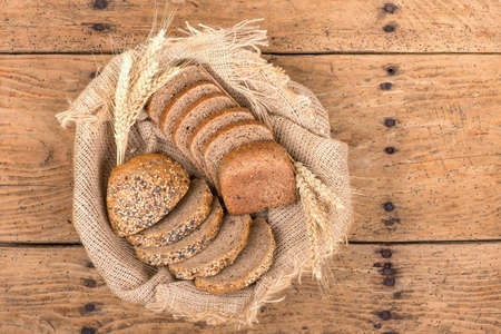 Rustic bread and wheat on an old vintage planked wooden table. Old wood background with free text...