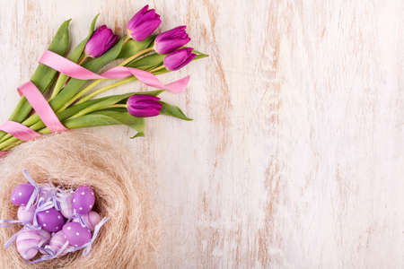 easter eggs and flowers over white wooden table - selective focus, copy space