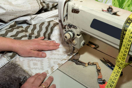 close up hands of seamstress working on sewing machine - copy space