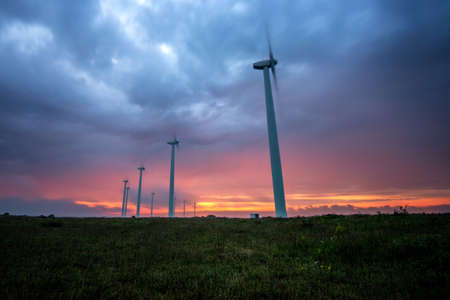 Wind turbines generating electricity against sunrise - copy spaceの写真素材