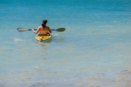 Young woman kayaking in the sea - selective focus, copy spaceの写真素材