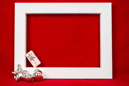 White wooden frame and a christmas gift over a red background - copy spaceの写真素材