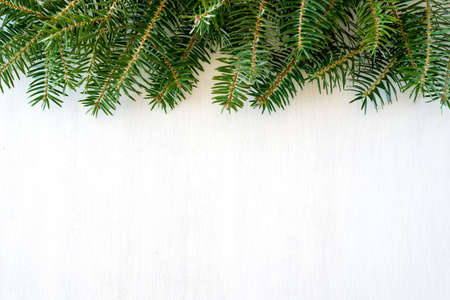 Christmas background - fir-tree branches frame isolated on white wooden backgroundの写真素材