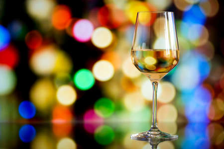 glass of white wine against a glowing bokeh - copy space, selective focusの写真素材