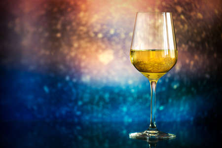 glass of white wine against a glowing bokeh - copy space, selective focusの写真素材