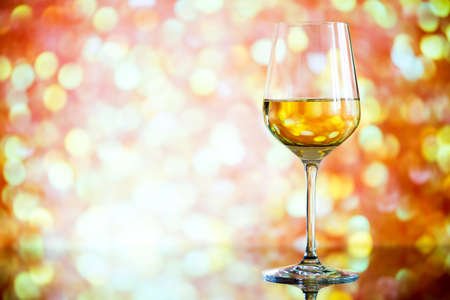 glass of white wine against a glowing bokeh - copy space, selective focusの写真素材