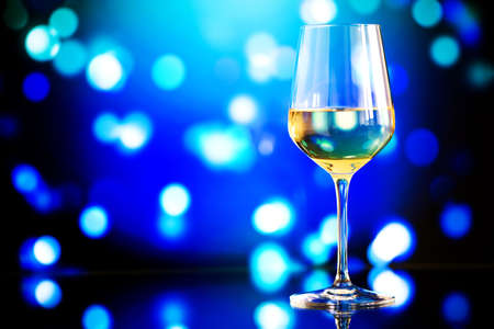 glass of white wine against a glowing bokeh - copy space, selective focusの写真素材