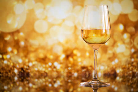 glass of white wine against a glowing bokeh - copy space, selective focusの写真素材