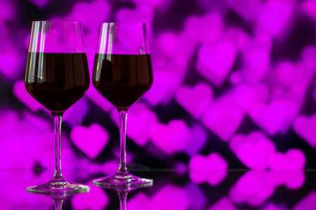 Two glasses of red wine against bokeh background with sparkles and roses. Very shallow depth of field. Selective focus, copy spaceの写真素材