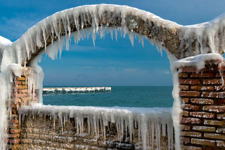Icicles over the arches of the abandoned swimming pool by the seaの写真素材