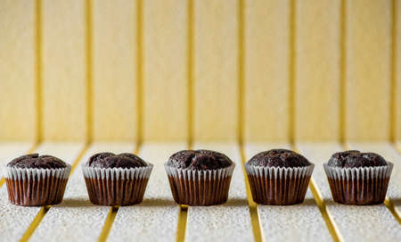 Chocolate muffins on a yellow rustic wooden table - selective focus, copy spaceの写真素材