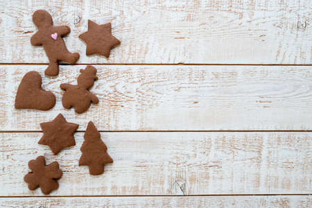 Christmas gingerbread cookies with different shapes over a white vintage wooden table