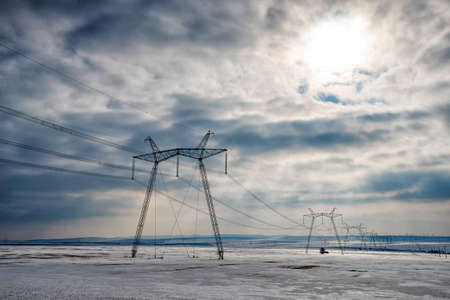 High voltage poles in a snow field in the winter - selective focus, copy spaceの写真素材