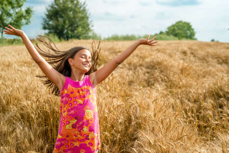 Happy little girl in a field of ripe wheat - selective focus, copy spaceの写真素材