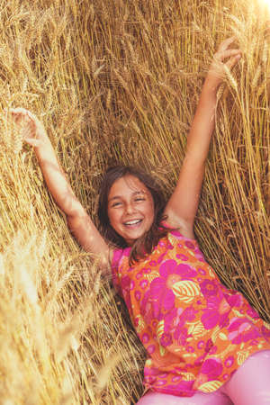 Happy little girl in a field of ripe wheat - selective focus, copy spaceの写真素材